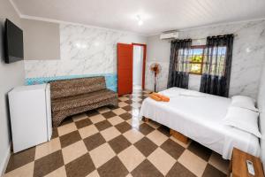 a room with two beds and a couch in it at Mandinga Guest house in São Tomé
