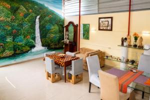 a living room with a table and a waterfall painting at Mandinga Guest house in São Tomé