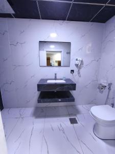 a white bathroom with a sink and a toilet at Hotel Ararat in Erbil