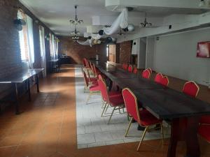 a long table in a restaurant with red chairs at Dworek kwatery pracownicze in Kętrzyn