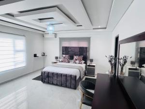 a white bedroom with a bed and a table and chairs at Kumnandi Guesthouse in Beacon Bay