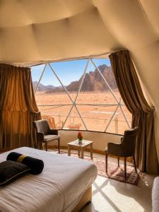 a bedroom with a bed and a large window at Norita Luxury Camp in Wadi Rum