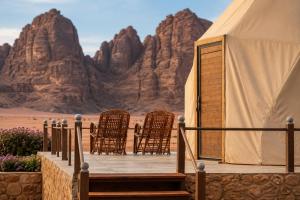 a tent with chairs and mountains in the desert at Norita Luxury Camp in Wadi Rum