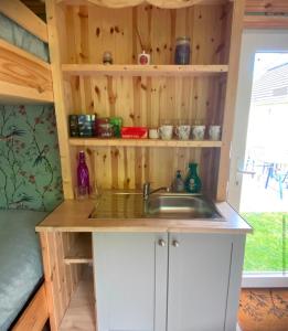 a kitchen with a sink and a wooden wall at Meadow Hut in Oughterard