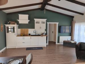 a kitchen with white cabinets and a green wall at La Brise des Fagnes in Jalhay +24 photos