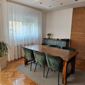 a dining room with a wooden table and green chairs at Apartment & Rooms Majetic-Draskovic in Bizovac