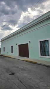 a white building with a brown door on a street at Casa Näab Centro de Merida in Mérida