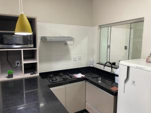 a white kitchen with a sink and a microwave at Vêneto Flat Residence (AP-13) in Primavera do Leste +3 photos
