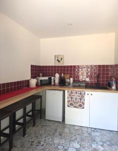 a kitchen with white cabinets and red tiles at Le ranch de Chant'alouette in Étauliers