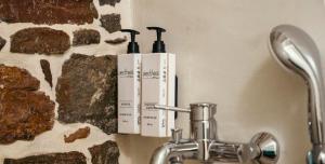 two bottles ofodorizers on a wall next to a sink at Rodakas Rooms-Adigoni in LivadhokhÃ³rion +22 photos
