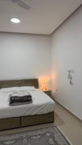 a bedroom with a large bed and a white wall at شقه مستقله بالقرب من مطار صلاله in Salalah