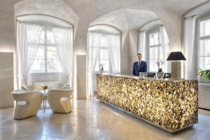 a man in a suit standing at a counter in a lobby at Three Storks in Prague