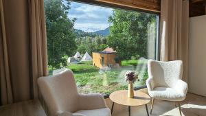 a room with a large window with two chairs and a table at Pura Vida Mountain Glamping-tiny houses and tents in Moieciu de Jos