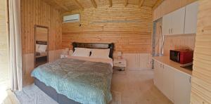a bedroom with a bed in a wooden room at Pura Vida Mountain Glamping-tiny houses and tents in Moieciu de Jos