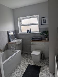 a bathroom with a tub and a toilet and a sink at Grange Retreat in Pontnewydd