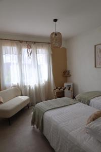 a bedroom with two beds and a chair and a window at Origines Be Holistic in Brengues