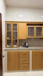 a kitchen with wooden cabinets and a counter top at شقه مستقله بالقرب من مطار صلاله in Salalah