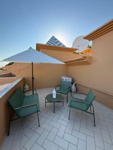 a patio with four chairs and a table and an umbrella at Moradia Almorávia in Olhos de Água