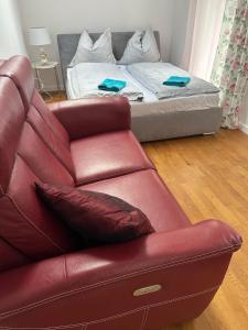 a living room with a red leather couch and a bed at Kościelnik Park Apartament in Lubań +2 photos
