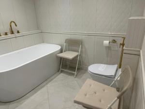 a white bathroom with a tub and a toilet at Kościelnik Park Apartament in Lubań