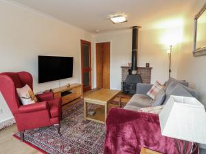 a living room with a couch and a tv at Steam Cottage in Aviemore