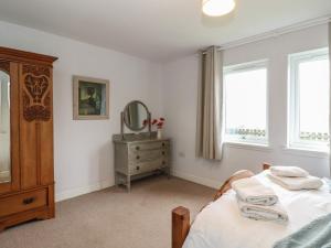 a bedroom with a bed and a mirror and a dresser at Poppies Cottage in Craignure