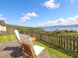 a pair of chairs sitting on a patio overlooking the water at Poppies Cottage in Craignure