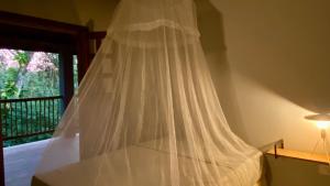 a white bed with a mosquito net next to a window at Pousada Refugio da Ilha Ilhabela in Ilhabela
