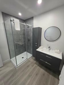 a bathroom with a shower and a sink and a mirror at Le 2020 Charlevoix in La Malbaie