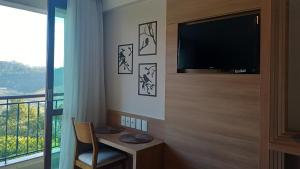 a room with a tv and a chair and a window at Hotel Apart Pedra Azul - Aracê - Domingos Martins in Domingos Martins