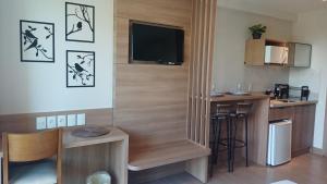 a room with a kitchen with a table and a television at Hotel Apart Pedra Azul - Aracê - Domingos Martins in Domingos Martins