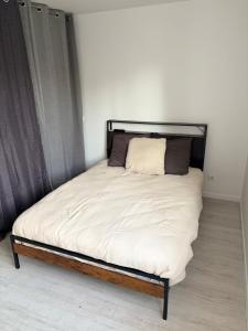a bed with a black frame and white sheets at Le clos du landreau in Saint-Père-en-Retz