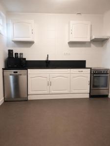 a kitchen with white cabinets and stainless steel appliances at Le clos du landreau in Saint-Père-en-Retz