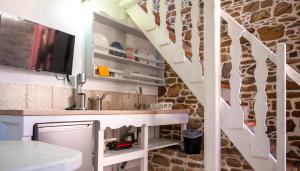 a kitchen with a stone wall and white stairs at Rodakas Rooms-Glikeria in LivadhokhÃ³rion