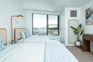 a white bedroom with two beds and a window at Central Upscale 2BR Condo wGym Office & Parking in Cambridge