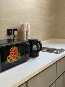 a microwave on a counter with a pizza on it at SORANO Apartments in Hail +18 photos