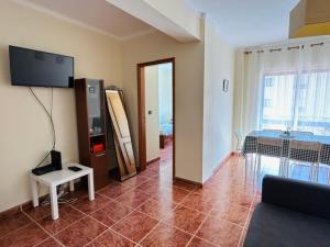 a living room with a couch and a tv on the wall at SwordFish Beach Escape Apartment in Atouguia da Baleia