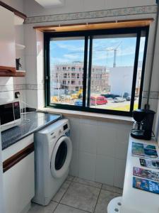 a bathroom with a washing machine and a window at SwordFish Beach Escape Apartment in Atouguia da Baleia