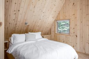 a bedroom with a white bed in a wooden wall at The Down-to-Earth in Rawdon
