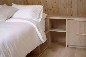 a bedroom with a white bed and a wooden wall at The Down-to-Earth in Rawdon