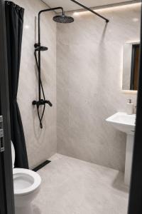 a bathroom with a shower and a toilet and a sink at SkyGate Hotel in Pʼarakʼar