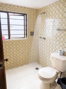 a bathroom with a toilet and a shower with a window at Hotel Bartolomé in Oaxaca City