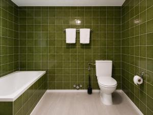 a green tiled bathroom with a toilet and a bath tub at Rivalago - Lake front apartment on Lake Promenade in Brissago