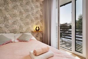 a bedroom with a pink bed with a balcony at Bocian Apartamenty in Krynica Zdrój