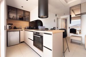 a kitchen with white cabinets and a stove top oven at Latsis Suites in Plytra