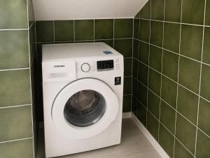 a washing machine in a bathroom with green tiles at Rivalago - Lake front apartment on Lake Promenade in Brissago