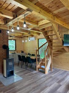 a dining room and kitchen in a log cabin with a table and a stove at Mazurski lasek in Szwejkowo