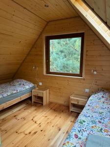 two beds in a log cabin with a window at Mazurski lasek in Szwejkowo