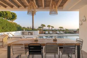 an outdoor dining area with a large wooden table and chairs at Sunset Sea View Villa with Private Pool in Sant Josep de sa Talaia