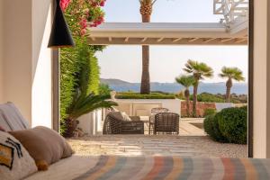 a bedroom with a view of a patio with palm trees at Sunset Sea View Villa with Private Pool in Sant Josep de sa Talaia